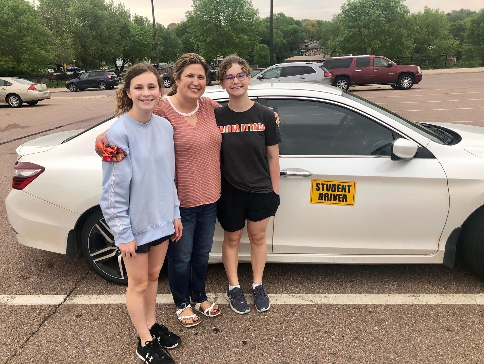 Kari standing by car with two students.